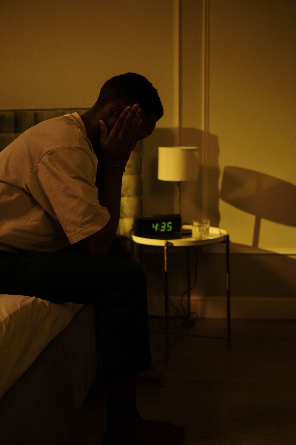 A man sitting on the edge of his bed awake at 4:35 am