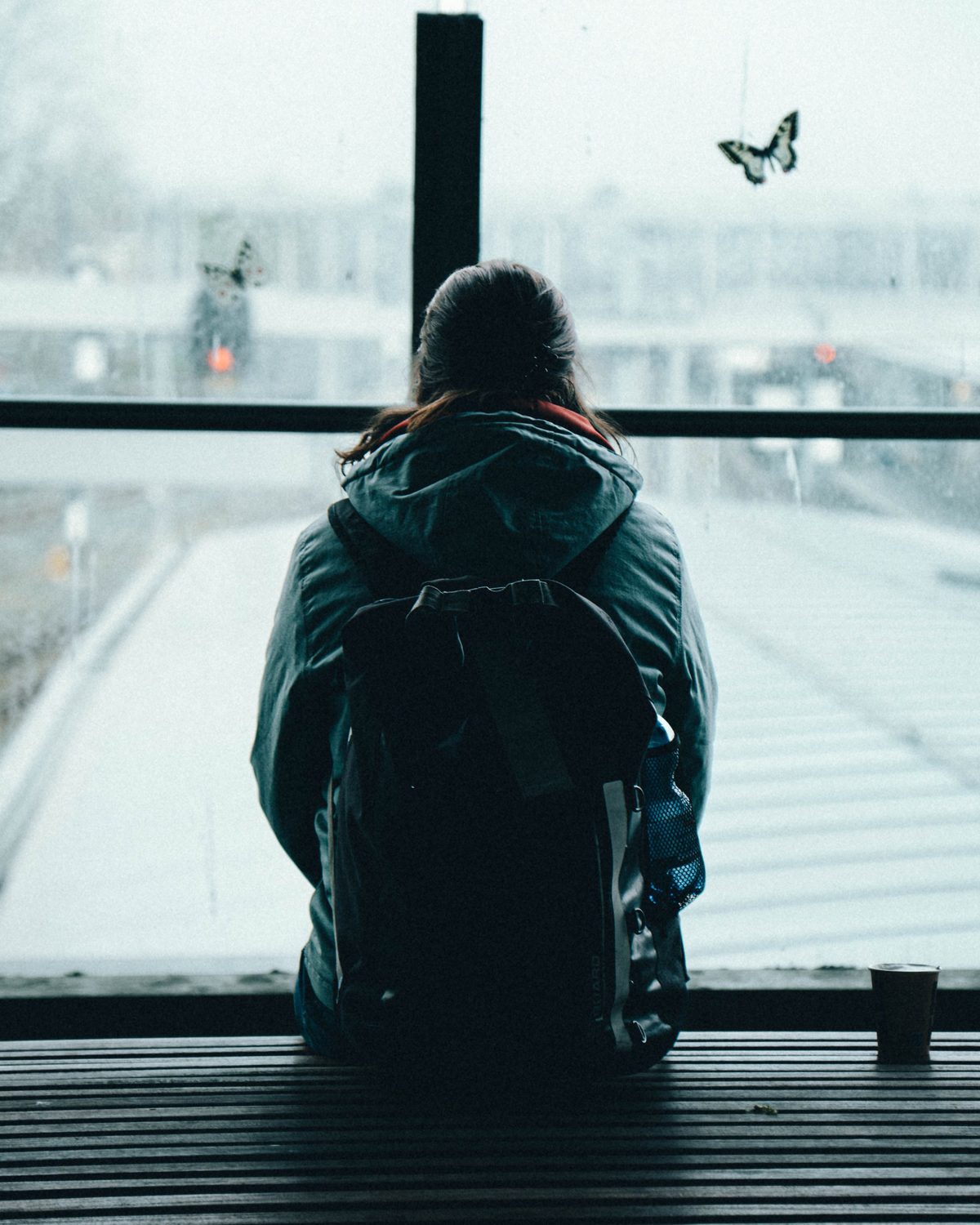 A person with a backpack looking out of a rainy window